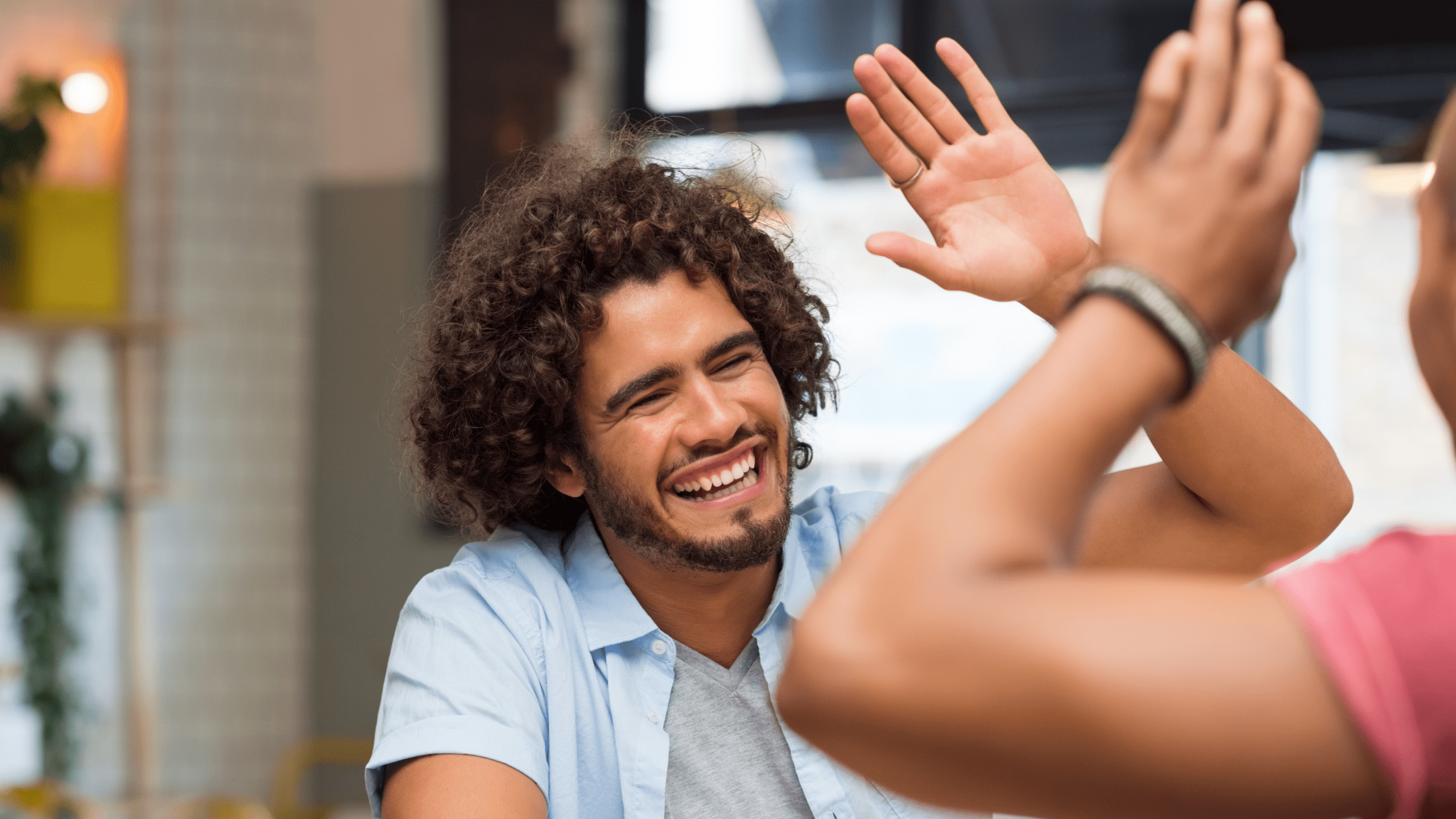 A young man smiles as he high-fives someone, symbolizing support and encouragement—key in overcoming academic struggles.